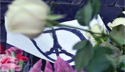  ??  ?? ROME: A photo taken on Saturday shows a peace sign next to flowers outside the French embassy in Rome, a day after a string of attacks on the French capital Paris. — AFP