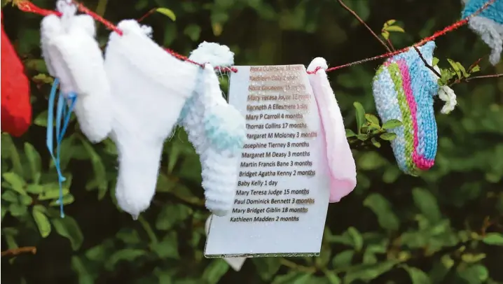  ?? Fotos: Niall Carson, PA Wire, dpa ?? An einer Friedhofsm­auer in Tuam hängen selbstgest­rickte und ‰gehäkelte Babysöckch­en. Ihre Farben leuchten im irischen Regenwette­r. Socken und Namenslist­en erinnern an all die Kinder, die in dem Ort starben.