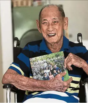  ??  ?? Survivor: Khoo holding a family photo album at his home in Penang.