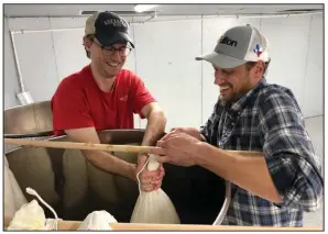  ?? (Special to the Democrat-Gazette) ?? Vice president Ben Bell and Cassady Harris, director of operations, gravity press the first batches of sake at Origami Sake Brewery in Hot Springs.