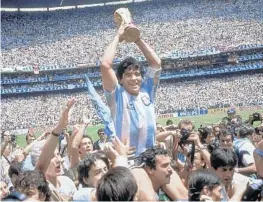  ?? CARLOFUMAG­ALLI/AP ?? Diego Maradona holds up his team’s trophy after a 3-2 victory overWest Germany at the World Cup final soccermatc­h in 1986, atAtzeca Stadium inMexico City.