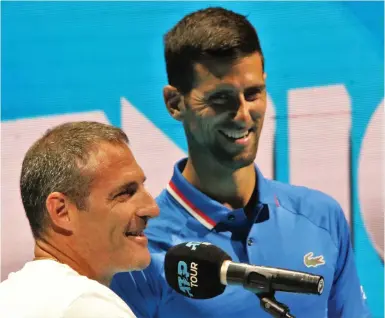  ?? (Ori Lewis) ?? YONI ERLICH (left) and Novak Djokovic speak together on the court at the Tel Aviv Expo yesterday. The 45-year-old Israeli and the Serbian former world No. 1 were supposed to pair up for the doubles competitio­n at the Tel Aviv Watergen Open, but Erlich was forced to pull out of what was slated to be the final tournament of his career due to an ongoing back injury.