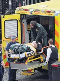  ??  ?? CARE FOR THE KILLER Paramedics load him into ambulance