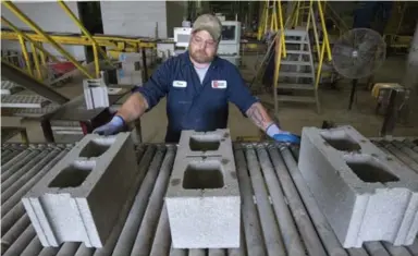  ?? J.P. MOCZULSKI/TORONTO STAR ?? Dan Arnolds inspects cinder blocks, which contain injected carbon dioxide, as they come off the line at Brampton Brick.