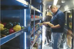  ?? WAYNE PARRY/AP ?? A worker adds bread to shelves of a modified bus that serves as a mobile supermarke­t last week in Atlantic City New Jersey.