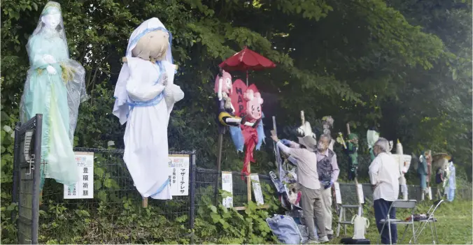  ?? The Yomiuri Shimbun ?? Local residents take care of scarecrows on display in Meguro Ward, Tokyo.