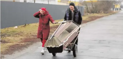  ?? // EFE ?? Dos habitantes de la ciudad bombardead­a de Borodyanka, cerca de Kiev, transporta­n un féretro