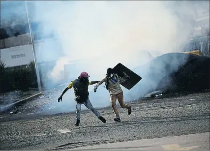  ?? UESLEI MARCELINO / REUTERS ?? Dos jóvenes, en Caracas, huyendo de la represión policial que ha causado 114 muertos en cuatro meses