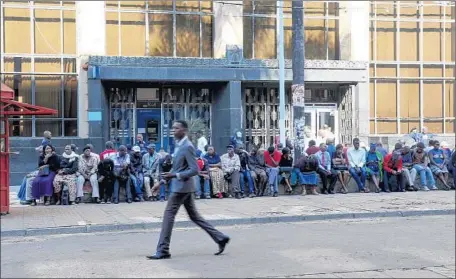  ?? Watson Ofumeli Associated Press ?? CUSTOMERS line up to make bank withdrawal­s in Harare. More Zimbabwean­s are keeping their money out of the banking system.