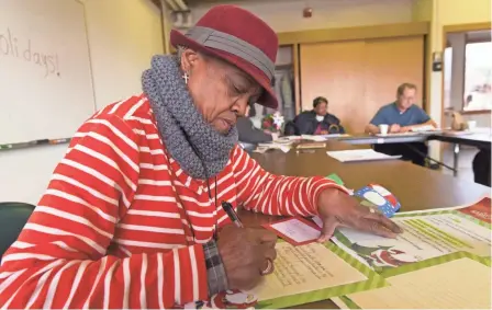  ?? MARK HOFFMAN / MILWAUKEE JOURNAL SENTINEL ?? Helen Dobson, 69, checks over a letter from Santa to a child on Thursday at the Washington Park Senior Center in Milwaukee.