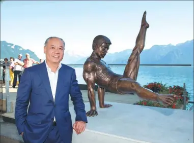  ?? XU JINQUAN / XINHUA ?? Li Ning, who won six gymnastics medals for China at the 1984 Los Angeles Olympics, poses with his statue on the shore of Lake Geneva in Montreux, Switzerlan­d. The statue depicts Li at the inaugural Arthur Gander Memorial in Montreux in 1985.