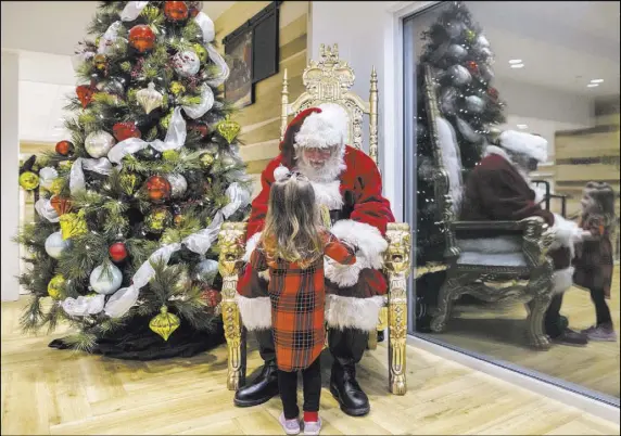  ?? BENJAMIN HAGER/LAS VEGAS REVIEW-JOURNAL ?? Santa Claus Barry Solomon greets Joanna Fountain, 2, at the Ethel M Chocolate Factory in Henderson. He has been part of the holiday celebratio­n at the candy company for 15 years. “I just love it,” said Solomon. “It’s the most rewarding experience of my...