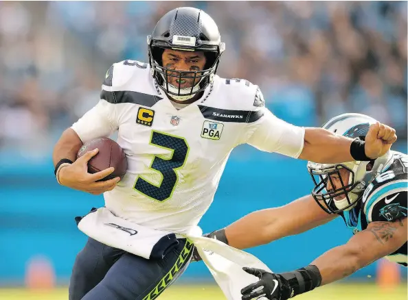  ?? GRANT HALVERSON / GETTY IMAGES ?? Seattle Seahawks quarterbac­k Russell Wilson constantly escaped pressure by Wes Horton and the rest of the Carolina Panthers on Sunday in Charlotte, N.C. Wilson threw a pair of touchdowns and 339 yards in rallying the Seahawks to a 30-27 victory.