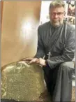  ?? PHOTO — SARAH KYRCZ ?? The Rev. Steven Hosking, of St. Alexis Orthodox Christian Church, with the gravestone of Robert Carter. The 1751 gravestone, found during the dismantlin­g of the stone smokehouse on church property, is temporaril­y in safekeepin­g at the church.