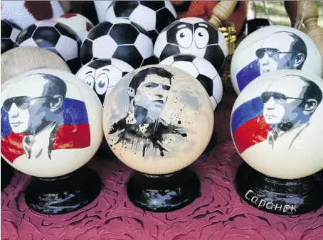  ?? THE ASSOCIATED PRESS ?? Balls depicting Russian President Vladimir Putin are sold as souvenirs alongside others bearing an image of Cristiano Ronaldo.