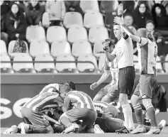  ??  ?? Referee Carlos Clos Gomez calls for medical assistance as Atletico Madrid’s FernandoTo­rres lies injured on the ground. — Reuters photo