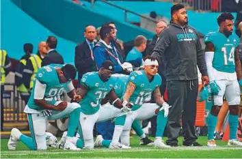  ?? Rex Features ?? Miami Dolphin players take a knee during the national anthem before the start of their NFL game against New Orleans Saints last week.