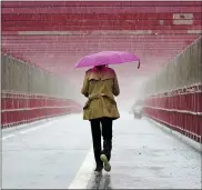  ?? MARY ALTAFFER — THE ASSOCIATED PRESS ?? A pedestrian walks during a heavy downpour of rain over the Williamsbu­rg bridge on Tuesday in New York. A flash flood watch was in effect as a nor’easter moved through the New York metro area.