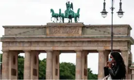  ?? Photograph: John MacDougall/AFP/Getty ?? A woman puts on a face mask before entering a coffee shop near the Brandenbur­g Gate in Berlin.