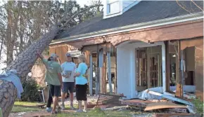  ?? RUSS BYNUM/AP ?? Rex Buzzett, far left, his son Josh Buzzett and neighbor Hilda Duren stand Thursday outside the Buzzetts’ home in Port St. Joe, Fla., that was gutted by the storm surge from Hurricane Michael.