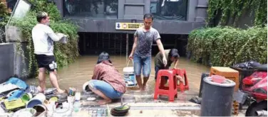  ?? Agence France-presse ?? ↑
Street food vendors clean the mud off plates and dishes after flooding in Jakarta on Sunday.