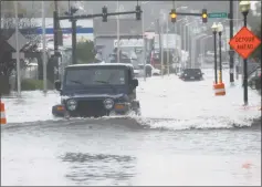  ?? Erik Trautmann / Hearst Connecticu­t Media ?? Motor vehicles try to make it through a closed Water Street in Norwalk after extreme high tide and storm surge flooded coastal areas on Oct. 27.