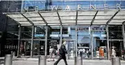  ?? [AP FILE PHOTO] ?? Pedestrian­s walk by an entrance to the Time Warner Center in New York. AT&T now says it’s “uncertain” when its $85 billion Time Warner purchase will close. AT&T had maintained that the deal would be done by the end of 2017.