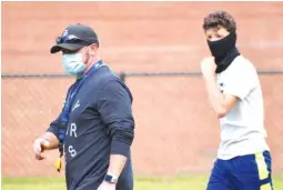  ??  ?? Red Bank High School assistant coach Brad Cowell and sophomore Jake Brune walk off the field wearning protective masks after Monday’s training.