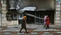  ?? Foto: Vahid Salemi, dpa ?? Am Tag danach: Passanten gehen an einer Bank vorbei, die bei den jüngsten Protesten in Brand gesteckt wurde.