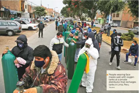  ?? Reuters ?? People wearing face masks wait with oxygen tanks at a private distributo­r that recharges tanks in Lima, Peru.