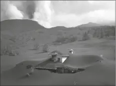  ?? EMILIO MORENATTI/AP ?? A HOUSE IS COVERED BY ASH from a volcano as it continues to erupt on the Canary island of La Palma, Spain, Saturday.