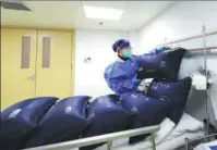  ?? FANG ZHE / XINHUA ?? A medical worker checks oxygen bags at Xietu subdistric­t community medical center in Shanghai, on Wednesday. Shanghai has expanded the capabiliti­es of its community medical centers so they can treat more COVID-19 patients amid the surge in cases in the city.