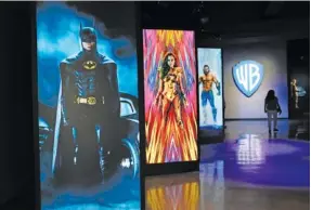  ?? AP PHOTO/CHRIS PIZZELLO ?? A visitor walks past portraits of DC Comics superheroe­s as she enters the “Action and Magic Made Here” interactiv­e experience at the Warner Bros. Studio Tour Hollywood media preview on June 24 in Burbank, Calif.