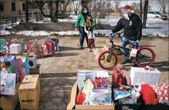  ??  ?? Jose Gonzalez wheels a bike past the dozens of presents Sunday (Dec. 20) at the Enos Garcia parking lot.