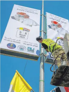  ?? FOTO: AMEER AL MOHAMMEDAW/DPA ?? Ein irakischer Arbeiter hängt Plakate zur Begrüßung von Papst Franziskus in den Straßen von Bagdad auf.