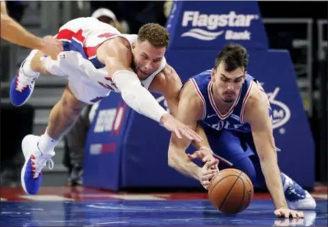  ?? CARLOS OSORIO — THE ASSOCIATED PRESS ?? Detroit’s Blake Griffin, left, and the Sixers’ Dario Saric reach for the loose ball during the second half on Tuesday in Detroit. Griffin scored 50 points as the Pistons won, 133-132.