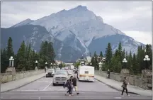 ?? Canadian Press photo ?? Pedestrian­s cross the street in Banff National Park in this July 2017 file photo.