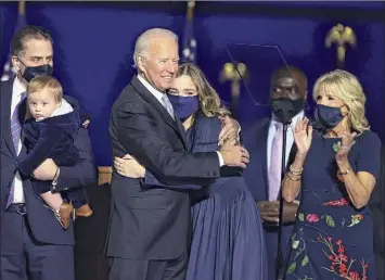  ?? Tasos Katopodis / Getty Images ?? President-elect Joe Biden hugs his granddaugh­ter on stage after Biden's address to the nation from the Chase Center Saturday in Wilmington, Del., as his wife, Jill Biden, looks on.