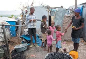  ??  ?? Mona Léger, vendeuse de charbon, donne de la nourriture à ses enfants dans le camp de réfugié de Caradeux. La famille vit toujours dans une tente depuis le séisme de 2008. - Associated Press: Dieu Nalio