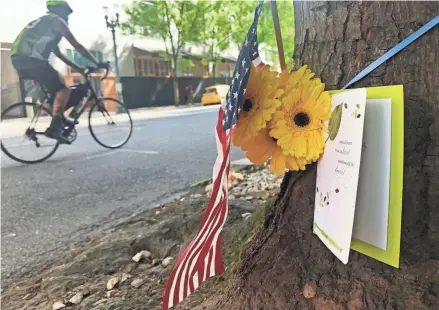  ?? GILLIAN FLACCUS/AP ?? A biker passes a makeshift memorial for Aaron J. Danielson, a supporter of President Donald Trump who was killed in a protest Saturday in Portland, Ore.