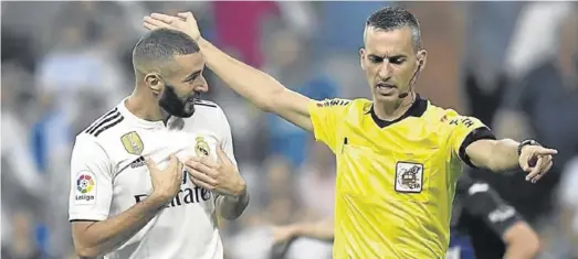  ?? AFP / GABRIEL BOUYS ?? Jaime Latre, árbitro de Primera de División, da indicacion­es de una jugada al delantero del Real Madrid Karim Benzema, que mira asombrado.