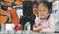  ?? CHEN BIN / FOR CHINA DAILY ?? A pupil watches a robotic arm in action during the fourth Digital China Summit in Fuzhou, Fujian province.