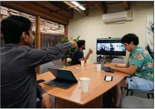  ?? (AP/Eric Risberg) ?? RunX Chief Executive Officer Ankur Dahiya (center) takes part in an office meeting with employees Nitin Aggarwal (left) and JD Palomino last month in San Francisco. Technology companies like RunX led the charge into remote work early in the pandemic.