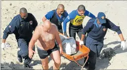  ??  ?? TRAGIC SCENE: Rescue workers carry the body of the murdered male student after it was recovered from the sea at Brighton Beach yesterday