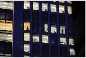  ?? (AP) ?? A man looks out of the window in December at an office building in Frankfurt, Germany. A new report says climate commitment­s by companies aren’t always as green as they seem.