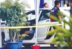  ??  ?? Forensics police personnel examining the car with the woman's body in the front passenger seat.