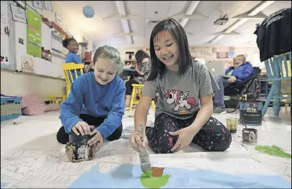  ?? HENRY TAYLOR PHOTOS / HENRY.TAYLOR@AJC.COM ?? Macy Becigneul (left) and Kiki Chen paint a large piece of paper that will later become a window of the restaurant at the third annual Kitchen Kids Café, an event where the Advanced Learning class runs an Italian restaurant at their school to collect...