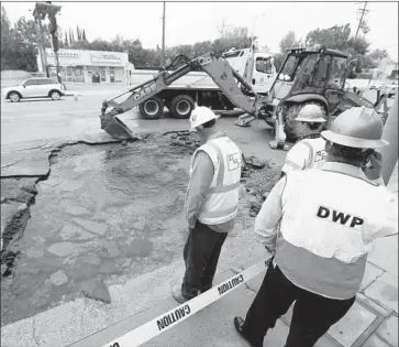  ?? Al Seib Los Angeles Times ?? DWP WORKERS examine a water main break on Tampa Avenue in Tarzana. The pipe was installed in 1967.