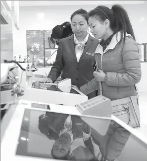  ?? XINHUA ?? An employee (center) of the Industrial and Commercial Bank of China addresses queries from a customer on wealth management products at a Beijing branch.
