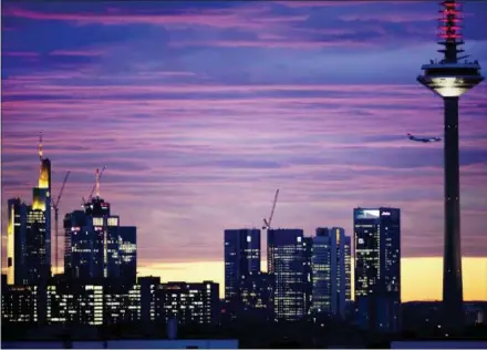  ?? MICHAEL PROBST — THE ASSOCIATED PRESS ?? An aircraft flies over the bank buildings and the television tower before sunrise Monday in Frankfurt, Germany.